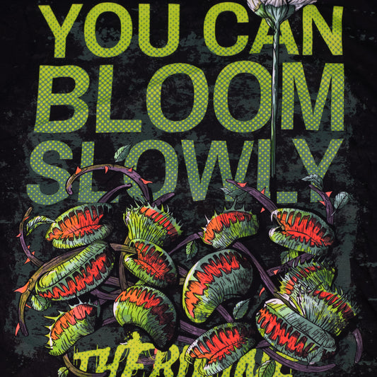 Black shirt with venus fly traps and one long, tall sprouting flower above. Text reads "you can bloom slowly" and a Therdune logo.