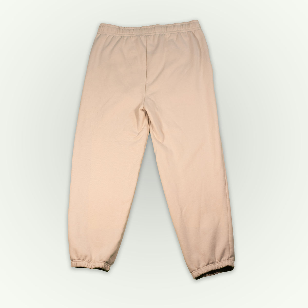 The back of dust colored fitted fleece pant, displayed flat against a light off-white background.