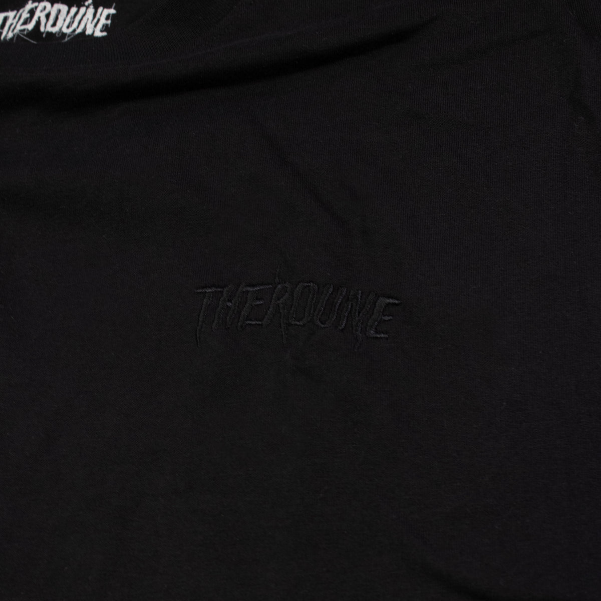 Close-up of a black T-shirt with tonal black embroidered 'Therdune' text on the chest.