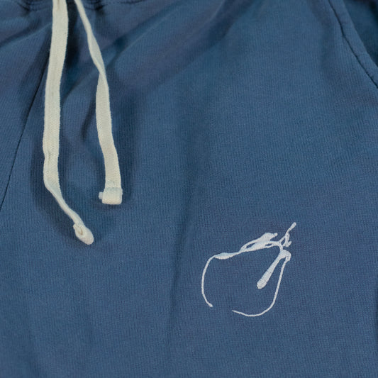 Close-up of blue jean colored fitted sweatpants laid flat. A white "Therdune Slug" logo is embroidered on the fabric.