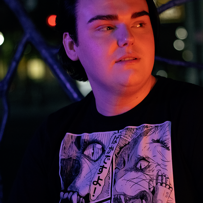 Black shirt with with 4 panel manga style illustration with japanese text and Therdune logo, worn by model, in urban setting.