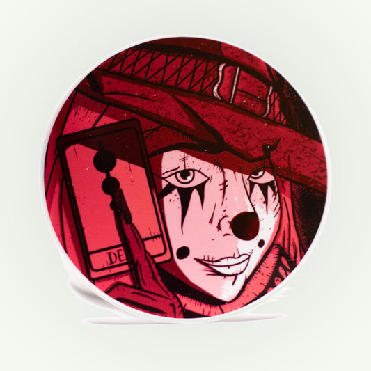 Circular product with a stylized face design wearing a red witches hat on a white background.