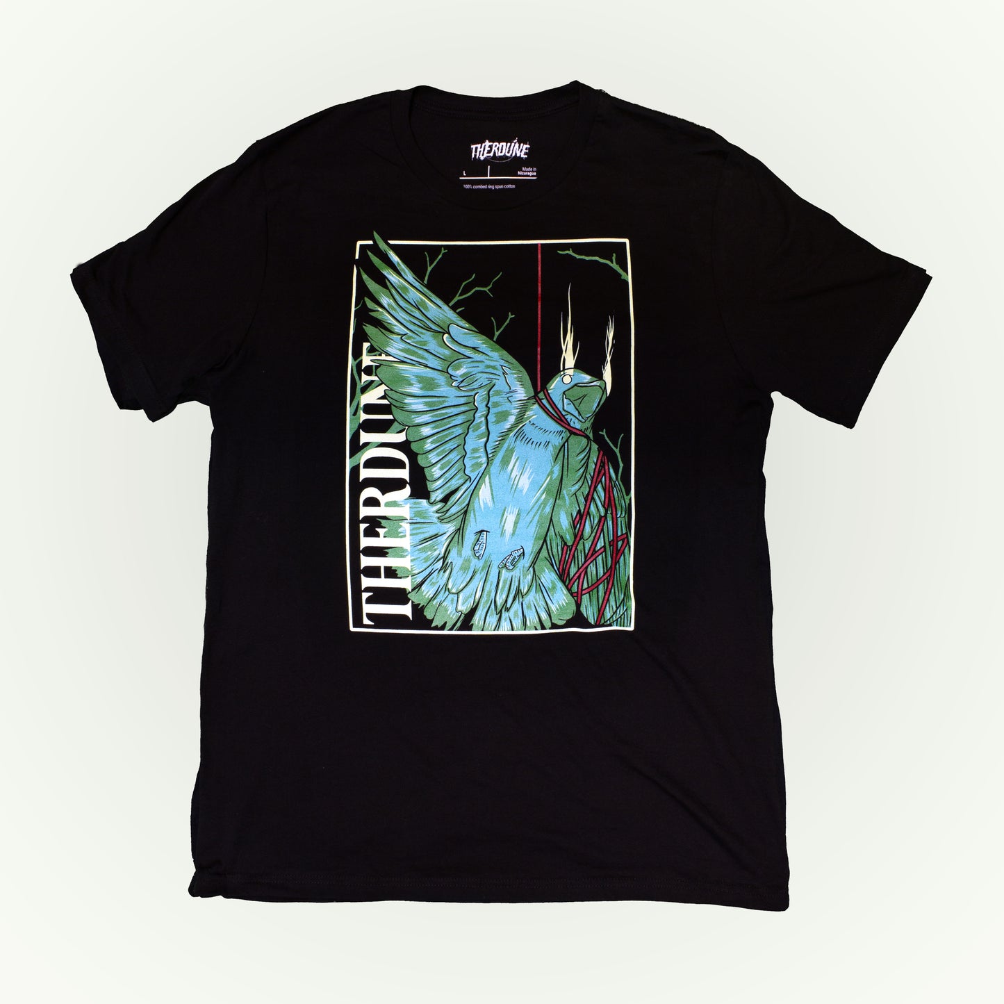 Black shirt with stylized graphic of a green bird, one wing and neck is wrapped up with a red piece of string. "Therdune" logo written on left side vertically. Flat lay on white background.