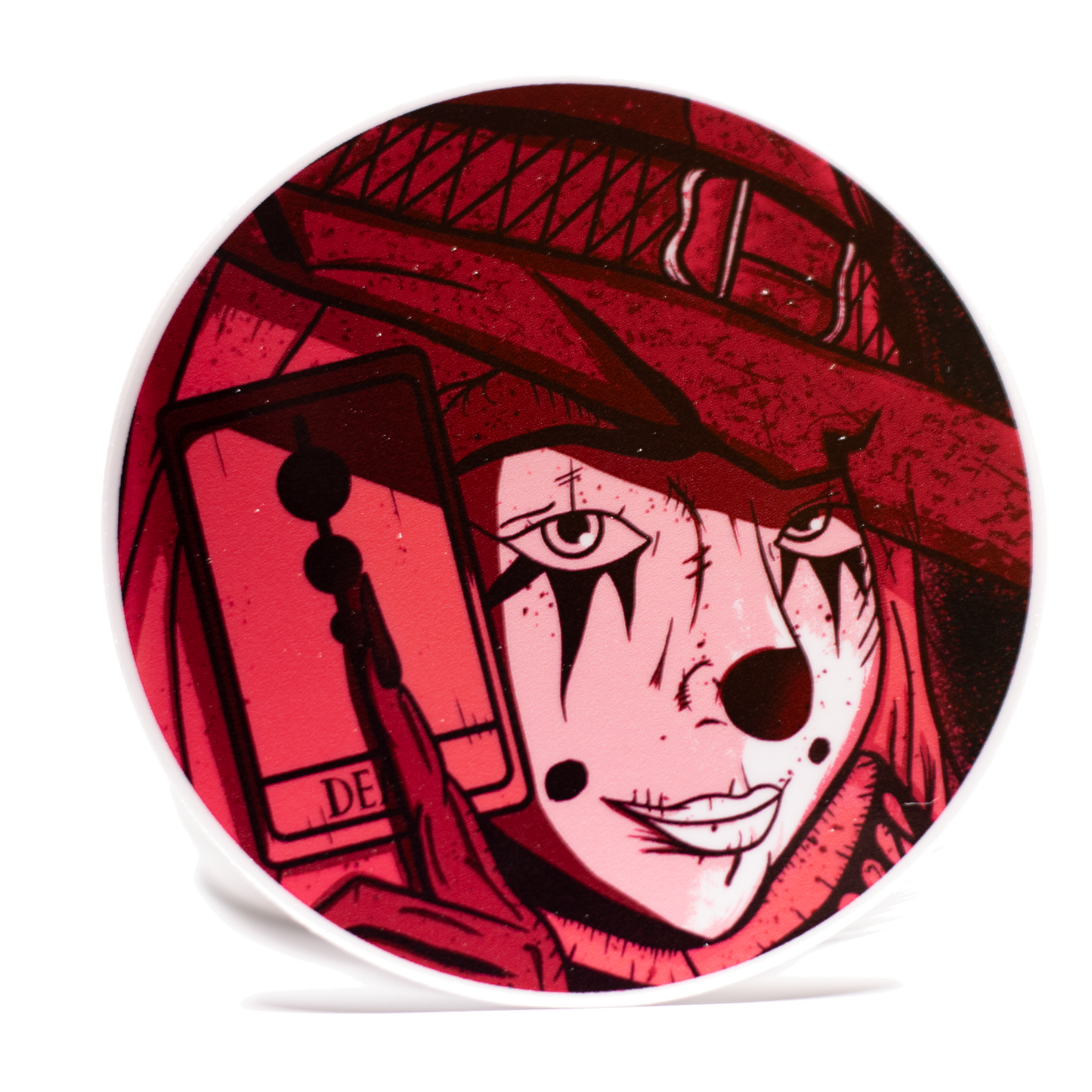 Circular product with a stylized face design wearing a red witches hat on a white background.