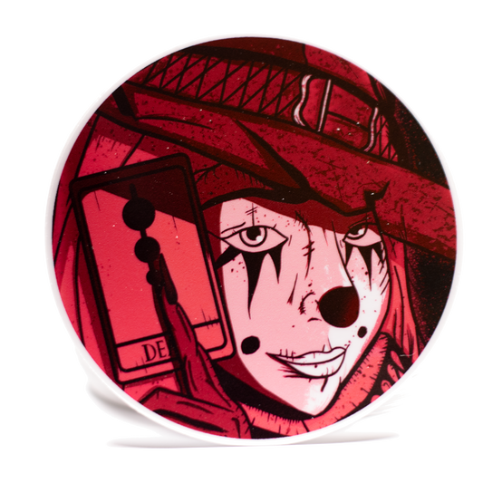 Circular product with a stylized face design wearing a red witches hat on a white background.