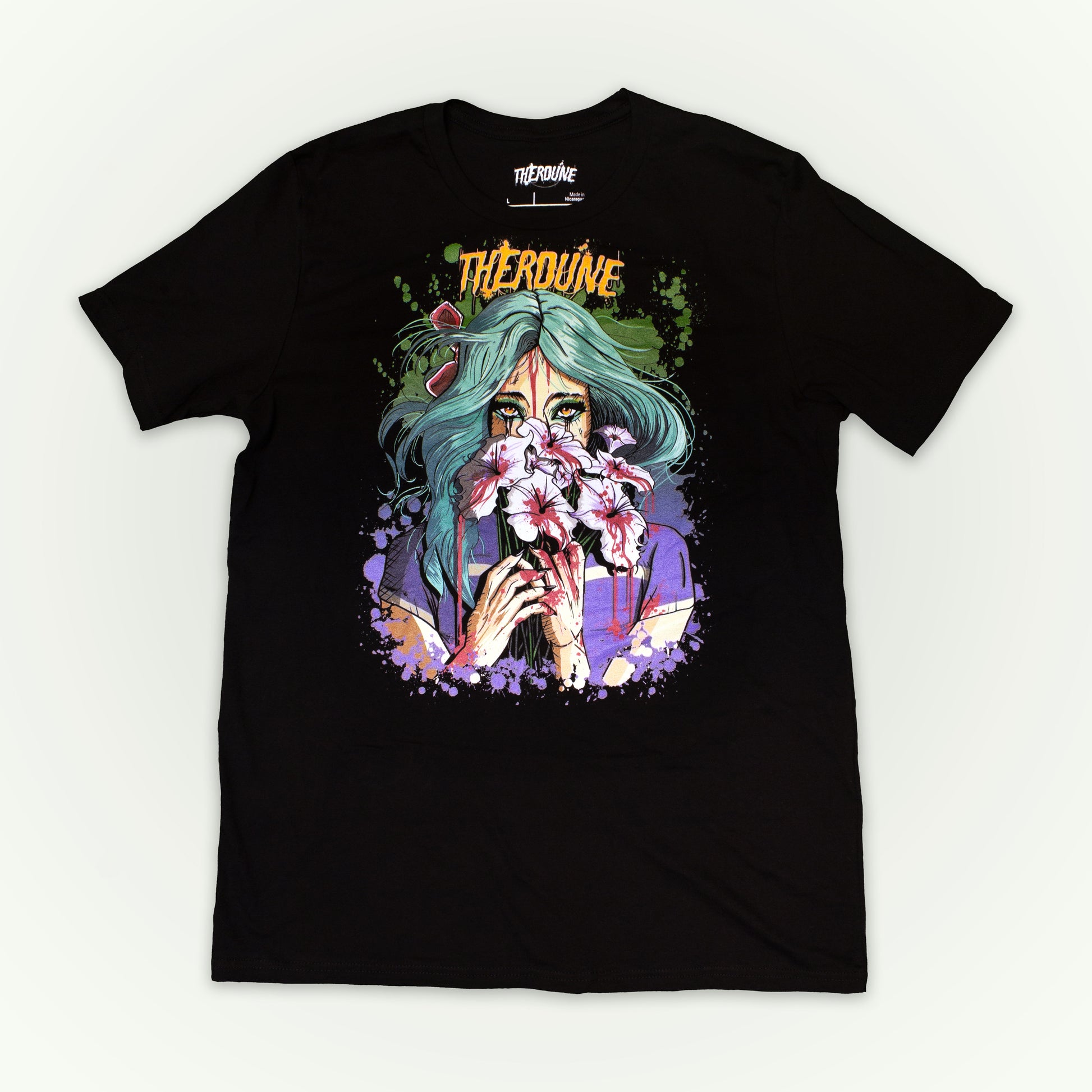 Black shirt with a stylized illustration of a person with teal hair and colorful makeup. Flat lay on white background.