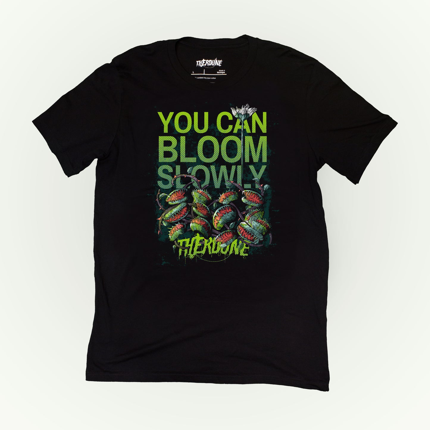 Black shirt with venus fly traps and one long, tall sprouting flower above. Text reads "you can bloom slowly" and a Therdune logo.