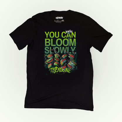 Black shirt with venus fly traps and one long, tall sprouting flower above. Text reads "you can bloom slowly" and a Therdune logo.