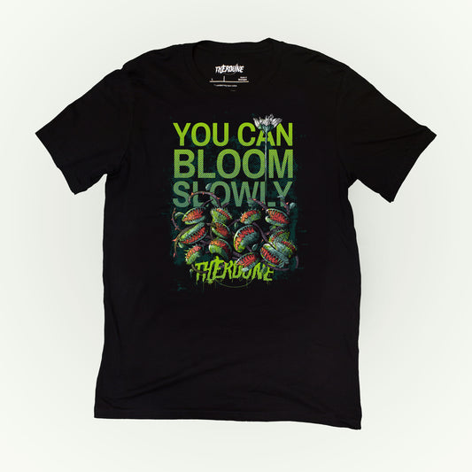 Black shirt with venus fly traps and one long, tall sprouting flower above. Text reads "you can bloom slowly" and a Therdune logo.