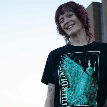 stylized graphic of a green bird, one wing and neck is wrapped up with a red piece of string. "Therdune" logo written on left side vertically. Worn by model in an urban setting.