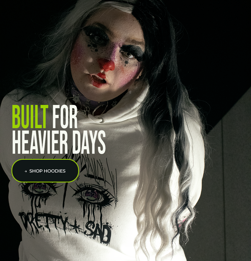 Person wearing a hoodie with artistic design and text, set against a dark background. A caption reads "built for heavier days". A button is labelled "shop hoodies" 