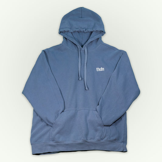 Blue jean colored hooded sweatshirt with a small white 'thdn' logo embroidered on the left chest, displayed flat against a light off-white background.