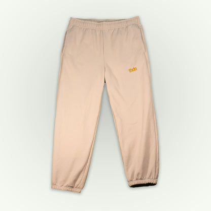 Dust colored fitted fleece pant with a small gold 'thdn' logo embroidered on the upper left thigh, displayed flat against a light off-white background.