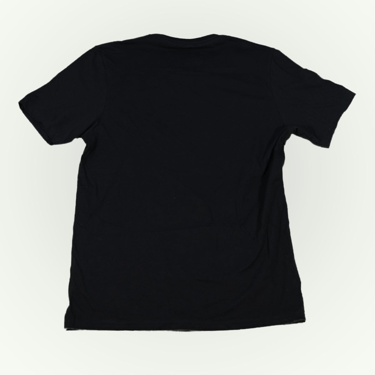The back of a plain black short-sleeve crewneck t-shirt shown from the back, laid flat against a light off-white background.