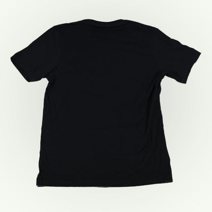 The back of a plain black short-sleeve crewneck t-shirt shown from the back, laid flat against a light off-white background.