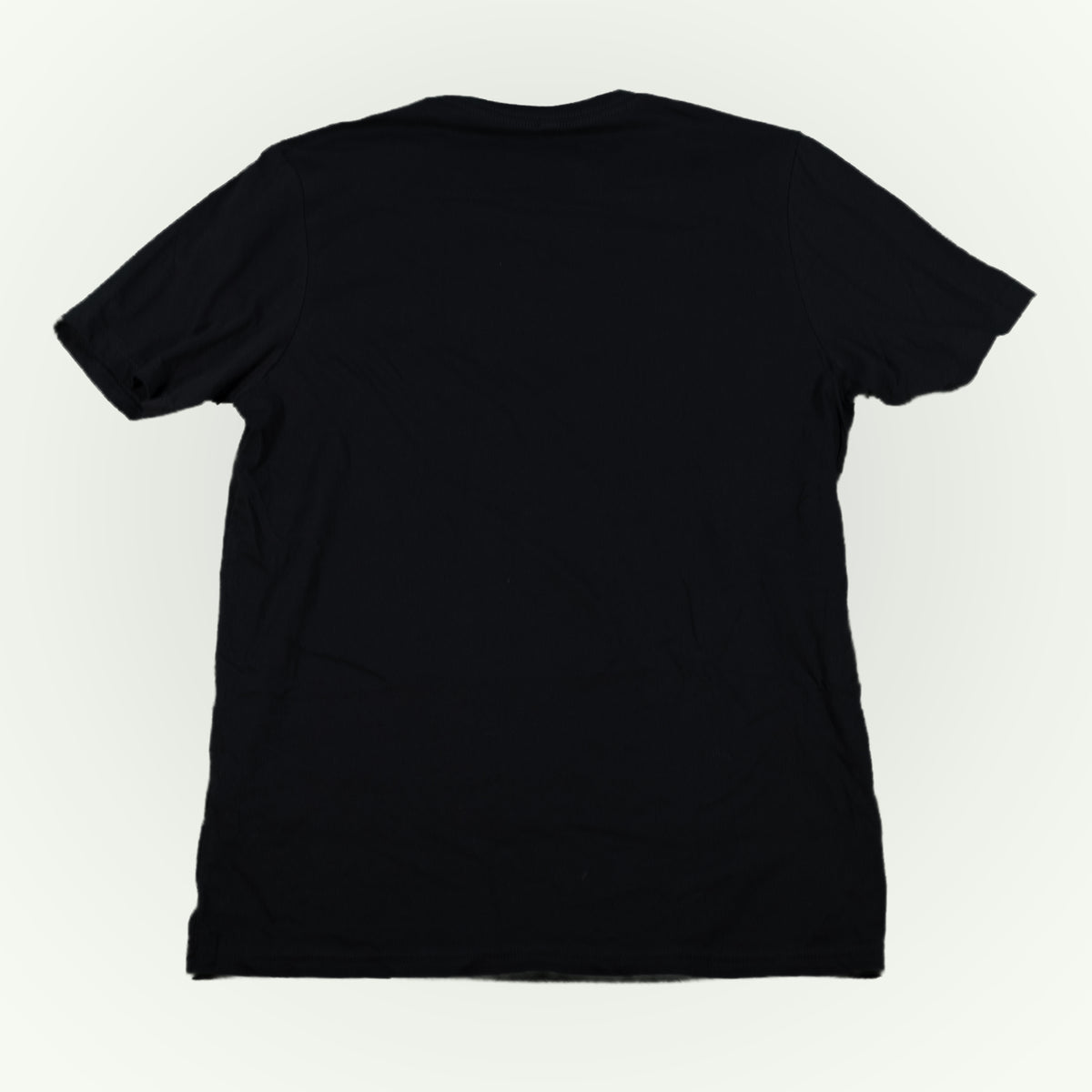 The back of a plain black short-sleeve crewneck t-shirt shown from the back, laid flat against a light off-white background.