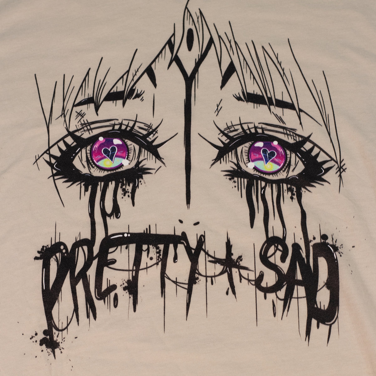Cream color shirt with a graphic print of stylized eyes and the text 'Pretty & Sad' on the front.