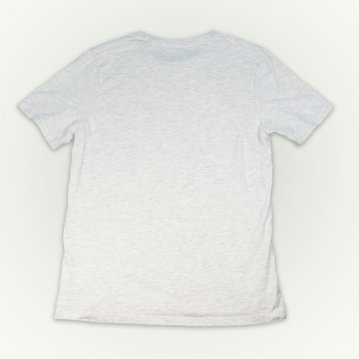 The back of a ash short-sleeve crewneck t-shirt laid flat against a light off-white background. 
