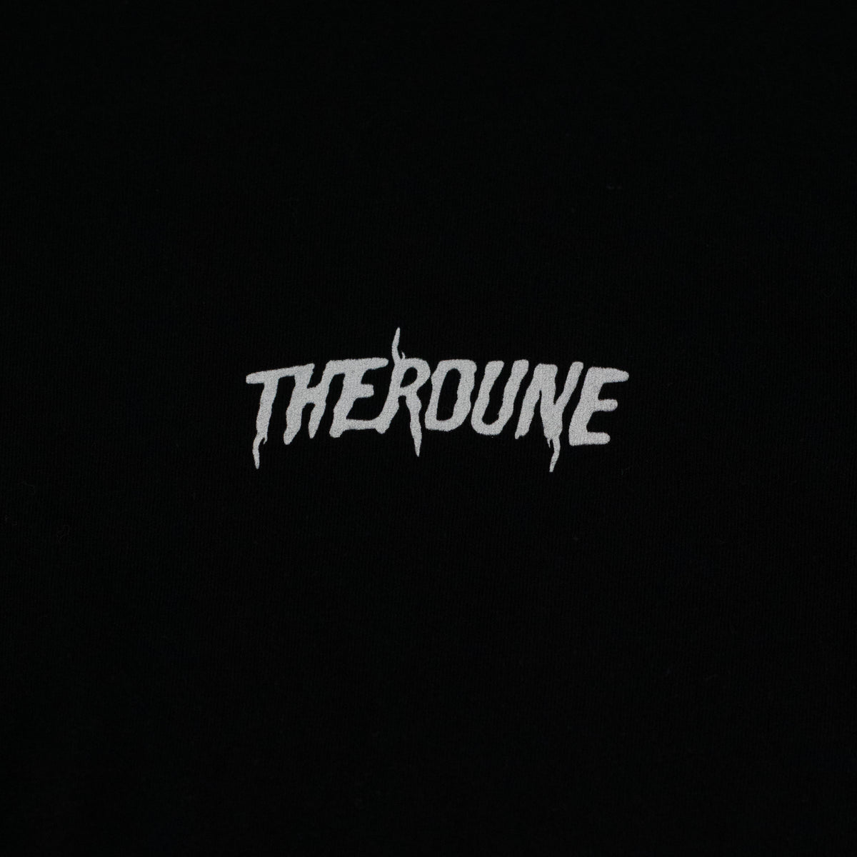 Close-up of a black short-sleeve crewneck t-shirt laid flat. A white Therdune logo is printed on fabric.