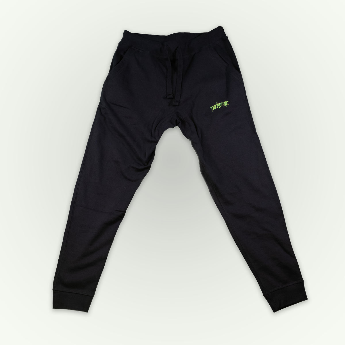 Fitted black jogger sweatpants with a small lime green 'Therdune' logo on the upper left thigh, displayed flat against a light off-white background.