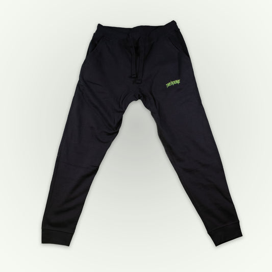 Fitted black jogger sweatpants with a small lime green 'Therdune' logo on the upper left thigh, displayed flat against a light off-white background.