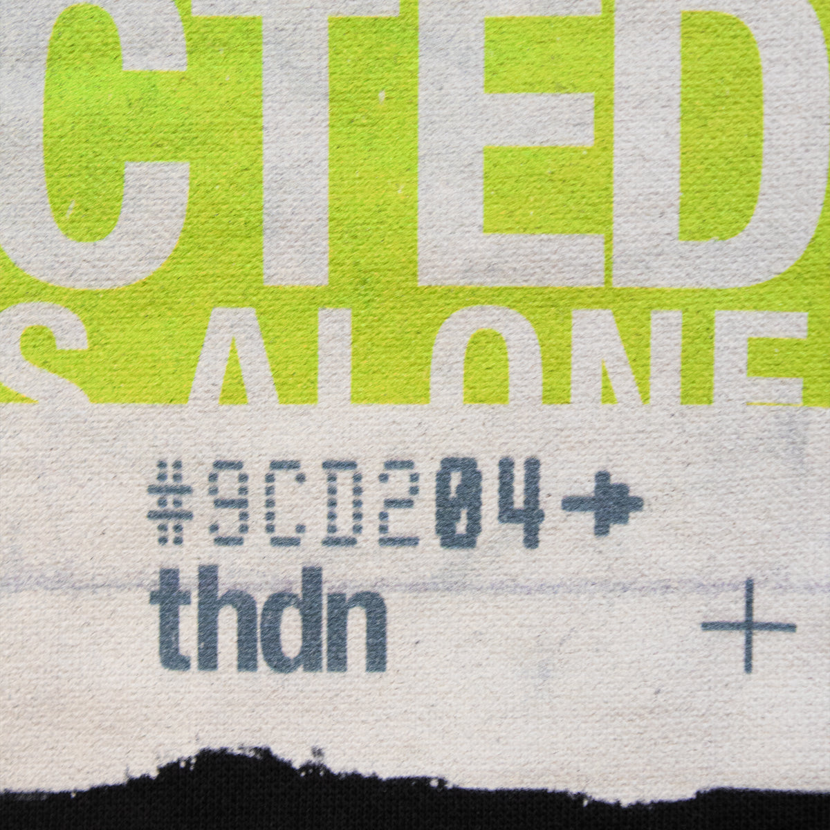Close-up of a printed textile or poster surface with large lime green and white text, gray numeric/lettered text reading 'thdn', and '#9cd204' with black torn-paper style band at the bottom.